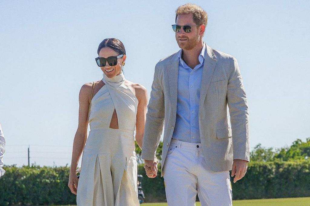 Meghan Markle, in a cut out cream dress, holds hands with Prince Harry, in white pants, blue shirt and grey blazer.