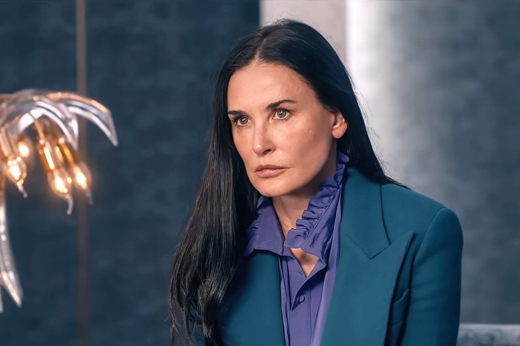 Demi Moore in a green jacket and purple shirt.