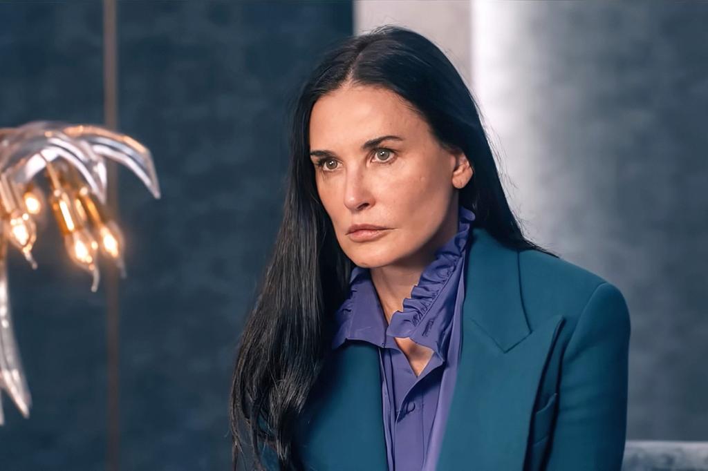 Demi Moore in a green jacket and purple shirt.